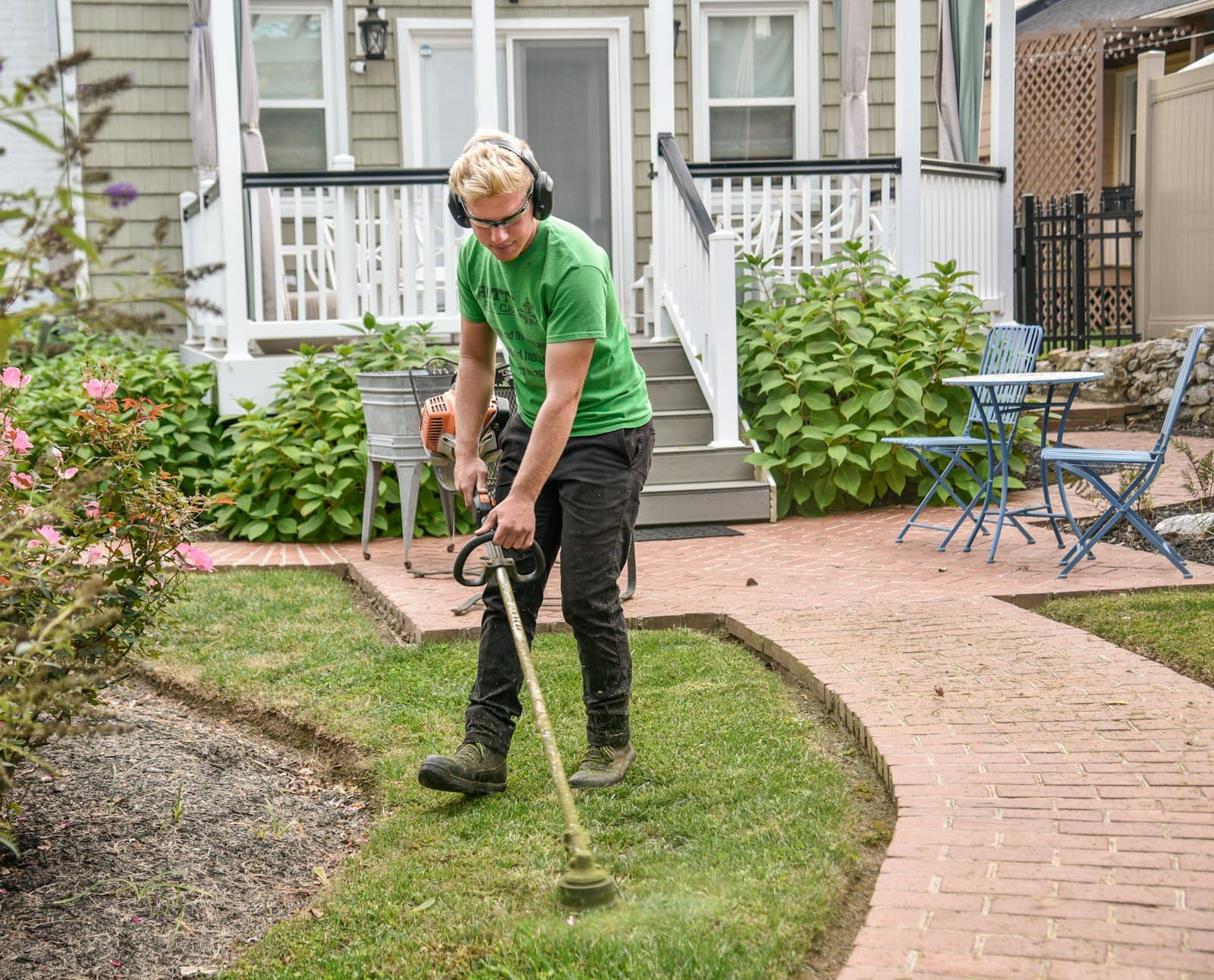 A crew member edging and trimming a landscaped front yard